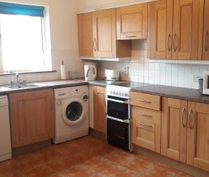 a kitchen with wooden cabinets and a washing machine at 18A Moore Bay Holiday Homes by Trident Holiday Homes in Kilkee