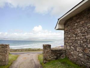 a stone building next to a road next to the ocean at The Lodge Rossbeigh by Trident Holiday Homes in Glenbeigh