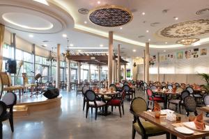 Holiday Inn - Suites Kuwait Salmiya, an IHG Hotel في الكويت: مطعم بالطاولات والكراسي والناس جالسين على الطاولات
