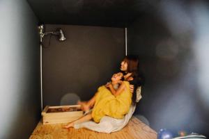 Eine Frau, die mit einem Mann auf einem Bett sitzt. in der Unterkunft Sunny Day Hostel in Takamatsu