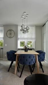 a dining room table with blue chairs and a chandelier at Apartament w samym sercu Opola 2 in Opole