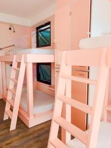 a pink bunk bed room with a ladder and bunk beds at Behind The Scene Hotel Club @ Samui in Chaweng