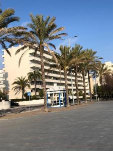 a building with palm trees in front of a phone booth at Face à La Mer in Calafell