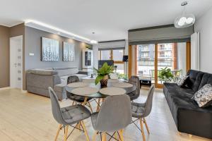 a living room with a table and chairs and a couch at Downtown Apartments Aura - Riverside & Parking in Gdańsk