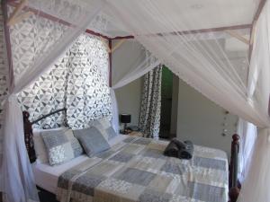 - une chambre avec un lit à baldaquin dans l'établissement IDC Guest House, à Bagamoyo