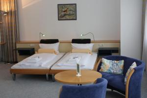 a room with a bed and two chairs and a table at Seepark Hotel am Wandlitzsee in Wandlitz