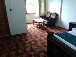 1 dormitorio con 1 cama, 2 sillas y mesa en Tourist Inn Hotel en Shogran