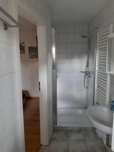 ein weißes Bad mit einer Dusche und einem Waschbecken in der Unterkunft Pension Lehmann in Radebeul