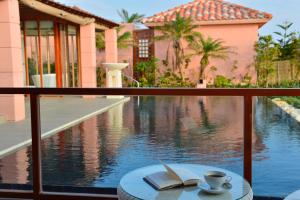 a cup of coffee and a book on a table next to a pool at The Shigira in Miyako-jima