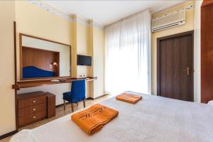 a bedroom with a bed and a desk and a mirror at Hotel Palladio B&B in Cervia