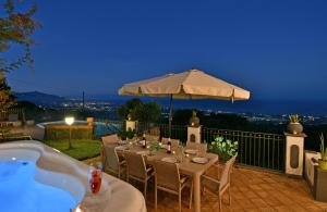 a patio with a table and an umbrella and a bath tub at Bellavista Etna in Mascali