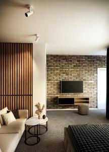 a living room with a couch and a tv on a brick wall at Privilege Suites by Central Park in Belgrade