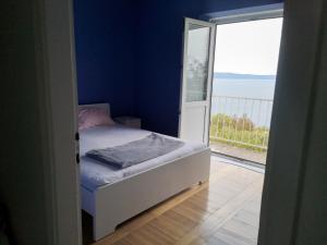 a small bedroom with a bed and a large window at Apartment Room with a view in Podgora