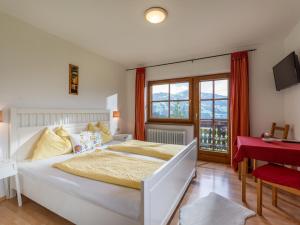 Schlafzimmer mit einem weißen Bett und einem roten Schreibtisch in der Unterkunft Weberhof Hopfgarten in Hopfgarten im Brixental
