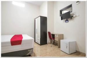 1 dormitorio con 1 cama, escritorio y TV en RedDoorz Syariah @ Jatinegara en Yakarta