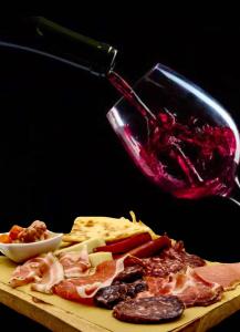 a cutting board with meat and cheese and a bottle of red sauce at Hotel La Ginestra in Acqualagna