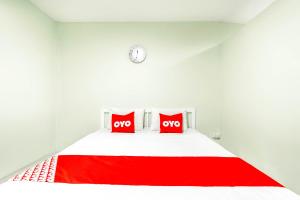 a white bedroom with two red pillows on a bed at OYO 722 I Oun Inn in Nakhon Nayok