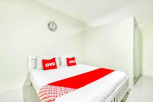 a white bedroom with a white bed with red pillows at OYO 722 I Oun Inn in Nakhon Nayok