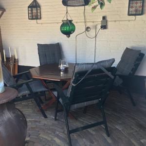 a wooden table with chairs and a green lamp at Bed and Breakfast Azzurro in Bokhoven