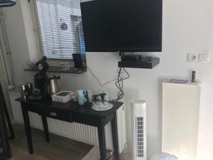 een tv aan een muur met een tafel met een televisie erop bij Bed and Breakfast Azzurro in Bokhoven