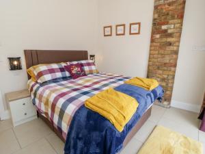 a bedroom with a bed with a checkered blanket at Plough Cottage in Great Driffield
