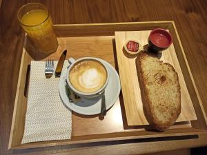 ein Tablett mit einer Tasse Kaffee und einem Laib Brot in der Unterkunft ARVA Spa París in León