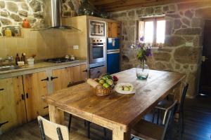 una cocina con una mesa de madera y un bol de fruta en Casa rural familiar con vistas al rio en Galicia en Puentesampayo