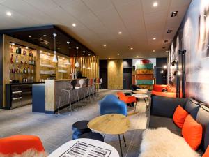 a bar with orange and blue chairs and tables at ibis Regensburg Zentrum in Regensburg