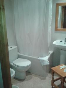 a white bathroom with a toilet and a sink at Hotel Bellavista in La Puebla de Castro