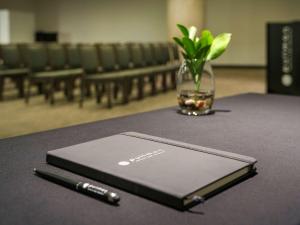 a notebook sitting on a table with a pen on it at Pullman Sharjah in Sharjah