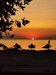 zachód słońca na plaży z parasolami i oceanem w obiekcie Isalos w mieście Velika