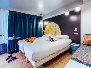 a hotel room with two beds with a dog laying on the bed at ibis Styles Le Treport Mers Les Bains in Mers-les-Bains