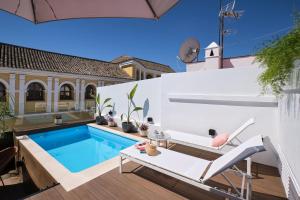 una piscina en un patio trasero con 2 sillas y una piscina en Sweet Sevilla Suites en Sevilla