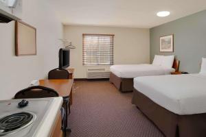 a hotel room with two beds and a desk at WoodSpring Suites Richmond Colonial Heights Fort Gregg-Adams in Colonial Heights
