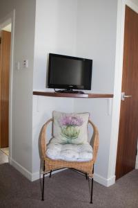 a chair with a pillow and a tv on a wall at Whitecroft B&B in Edinburgh