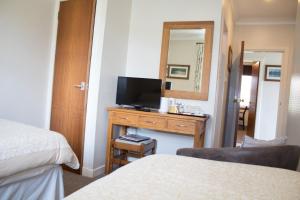 a room with two beds and a television on a dresser at Whitecroft B&B in Edinburgh