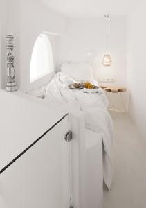 a white bedroom with a bed and a table at Dana Villas & Infinity Suites in Firostefani