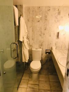 a white toilet sitting next to a bath tub in a bathroom at Beach Luxury Hotel in Karachi