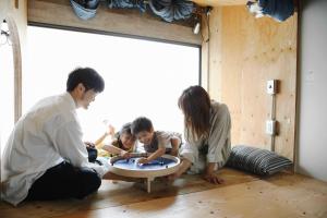 een gezin dat met een tafel in een kamer speelt bij Sunny Day Hostel in Takamatsu
