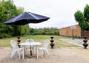 une table avec un parasol noir et deux chaises blanches dans l'établissement Euro Hotel Harrow, à Harrow