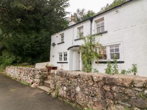a white house with a stone wall at Yew Tree Cottage in Ravenglass