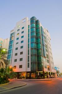um grande edifício com janelas de vidro numa rua da cidade em One Pavilion Luxury Serviced Apartments em Manama