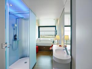 a bathroom with a sink and a shower and a bed at citizenM Paris Charles de Gaulle Airport in Roissy-en-France