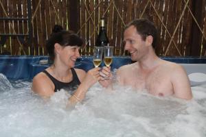 un hombre y una mujer en un jacuzzi con copas de vino en The Cables, en Matlock