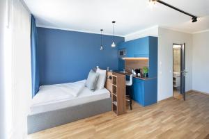 um quarto com paredes azuis e uma cama com uma secretária em Brera Serviced Apartments Ulm em Ulm