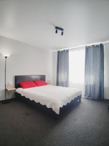 1 dormitorio con 1 cama blanca grande con almohadas rojas en Міни - готель в центрі Apartment in Center, en Rivne