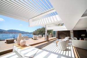 un patio con muebles blancos y vistas al agua en Hôtel Marinca & Spa en Olmeto