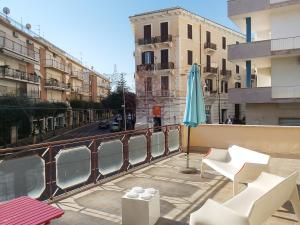 a balcony with chairs and an umbrella and a street at Bed a Cavour in Gaeta