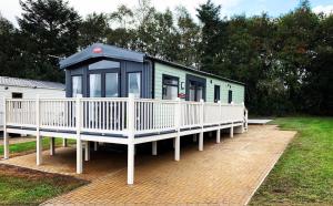 a mobile home with a porch and a white fence at Lola Lodge - Luxury Hot Tub Retreat in Newton on the Moor