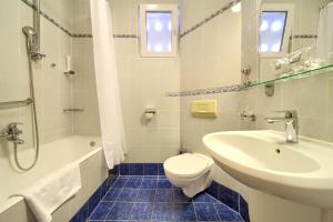 a white bathroom with a sink and a toilet and a tub at Hotel Dražica - Hotel Resort Dražica in Krk